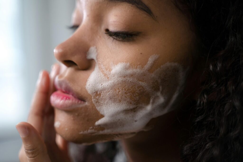 Woman gently cleansing her face with lukewarm water and gentle facial cleanser