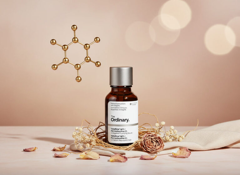 Close-up product photograph of a 30ml The Ordinary Hyaluronic Acid 2% + B5 serum in a dark amber glass dropper bottle with silver cap, centered on a soft beige fabric with scattered dried rose petals, eucalyptus leaves, and dried flowers in a nest-like arrangement; a large metallic molecular structure model glows in golden bokeh lights on the upper left, evoking luxury skincare elegance.
